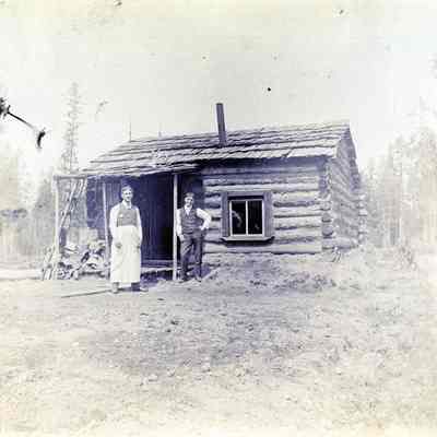 Unknown Log Cabin with Two men Standing in Front
