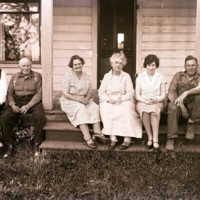 Men and Women (unknown) sitting in front of house - Negative