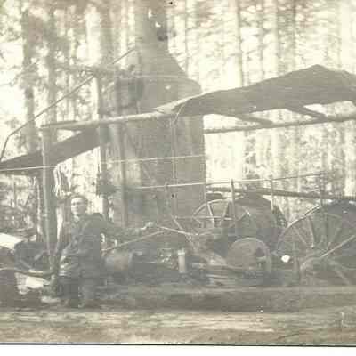 Postcard of a man in front of Lumber Equipment