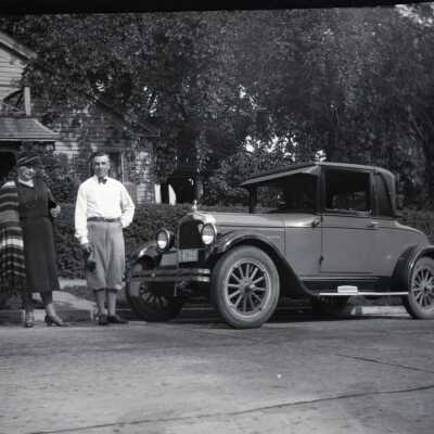Man and Woman with Car in Front of House.