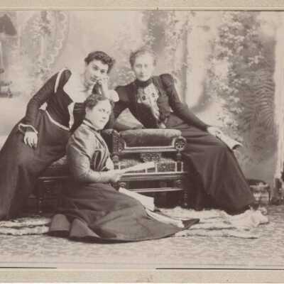 Three Unknown Ladies Sitting Around Chair - E.G. Caufield Coll