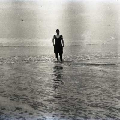 Woman in Swimwear, Standing in Surf at Beach.