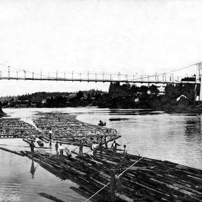 Log rafts in Willamette River below suspension bridge.