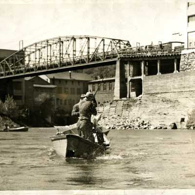 Photograph two unknown men catching a fish