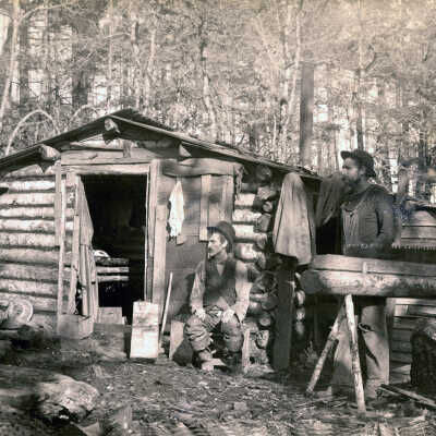 Three men/boy outside log cabin.