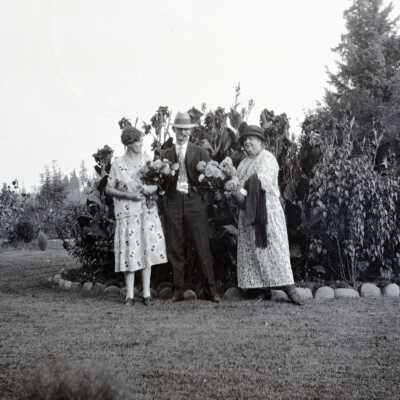Two Women and a Man Holding Flowers.