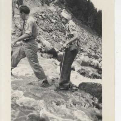 Two men walking across creek