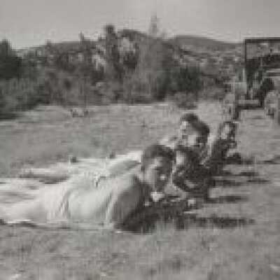 Unknown People laying on grass with jeep in background