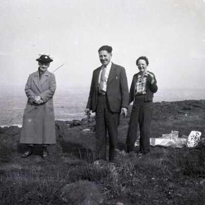 Two Women and a Man Standing Outdoors.