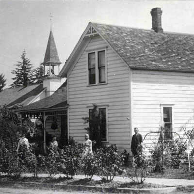 **Verify** Mr. and Mrs. Clack at home with the United Brethren Church in the background, Oregon City.