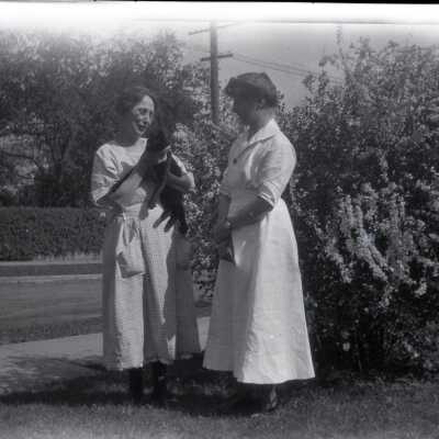 Two Women Beside Flowering Bush.