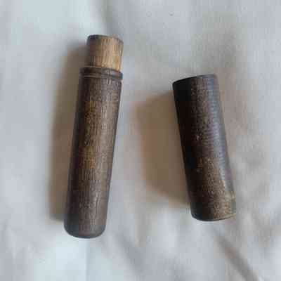 Two rustic, cylindrical wooden pieces rest on a white fabric background