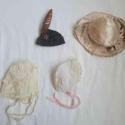The image shows four vintage doll hats on a white surface