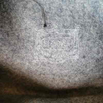 The image shows an interior label of a hat, stamped onto soft grey fabric.