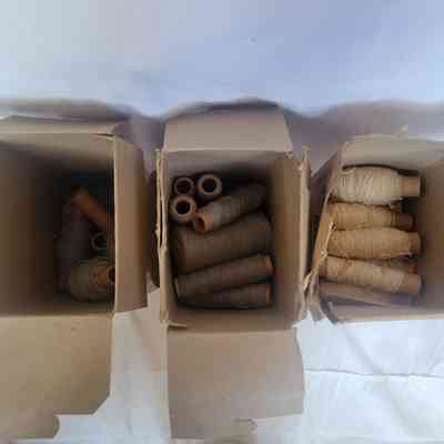 Three cardboard boxes display an assortment of spools with different colored threads nested inside.