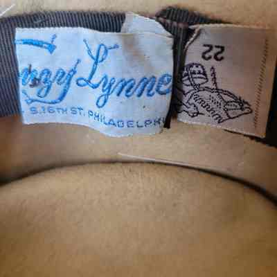 This image shows a hat label with blue writing and a size label marked as 22.