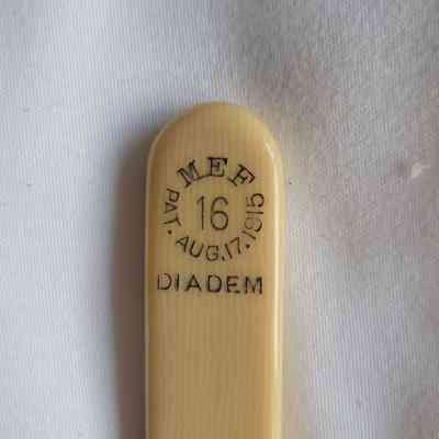 The image shows a close-up of a beige object with inscriptions: "MEF 16, PAT.AUG.17.1915, DIADEM"