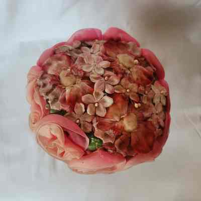 The top of the hat, covered in pink fabric flowers of different types and styles.