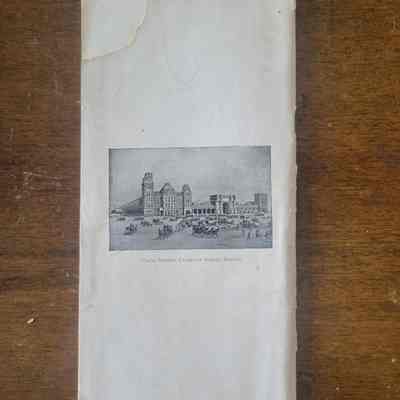The back of the booklet with a captioned illustration of Boston, MA on a white page. Displayed on a wooden background.
