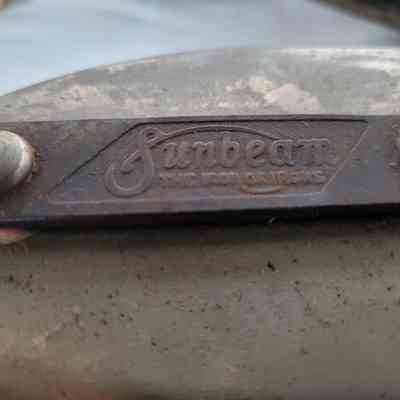 The image shows a close-up of an old metal object with "Sunbeam" engraved, featuring rust