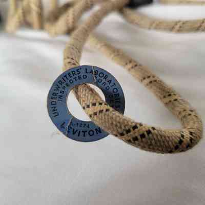A braided fabric electrical cord with a blue Underwriters’ Laboratories inspection tag is shown.