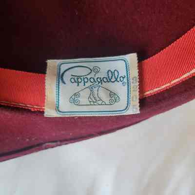 The image shows a red hat with a fabric label reading “Pappagallo” and featuring decorative