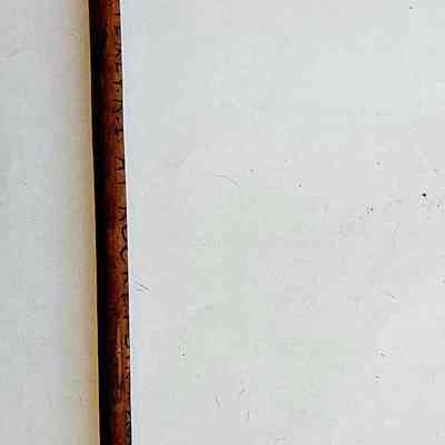 Walking Cane: The image shows a wooden walking cane with a curved, black handle lying against a plain white background.