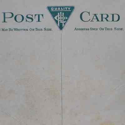 A white card with green printing, divided by a line down the center. There is a triangular logo at the top of the dividing line and labels for the message and address on either side.