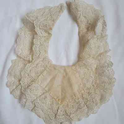 The image shows a vintage lace bib on a white surface.