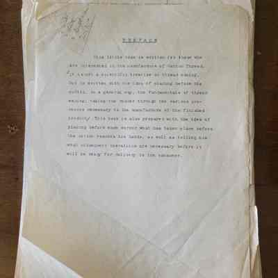 A stack of yellowed, creased, and torn sheets of onionskin pages on a wooden background. There is typewriting on the top half of the top page and pencil notes on the top left.
