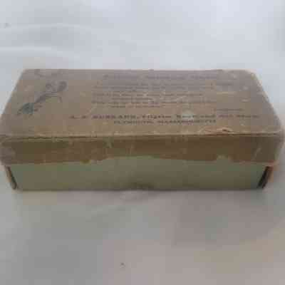 The image shows an old, worn rectangular box with text and illustrations on its lid.