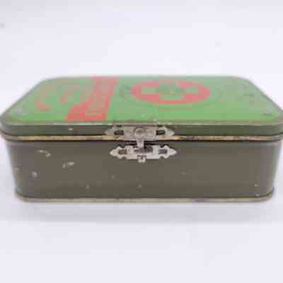 The image shows a vintage, metal first aid tin box with a green lid and red cross.