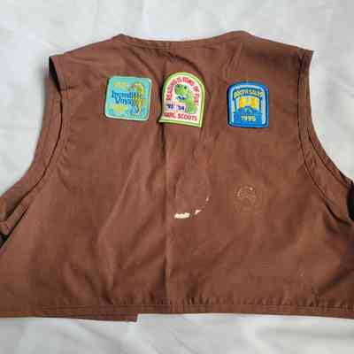 The brown vest displays multiple colorful patches, each representing achievements earned over various years.