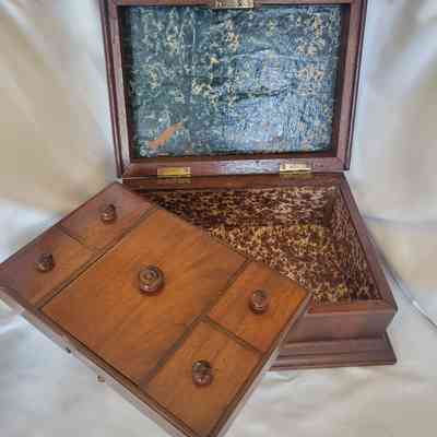 The image shows an open wooden box with small knobs and a textured interior surface