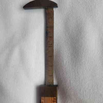 The image shows a vintage ruler with extended caliper with engraved measurements.