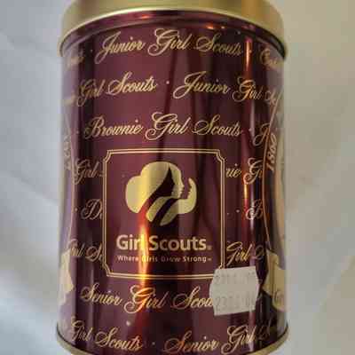 The image shows a maroon tin with gold lettering of Girl Scouts branding prominently displayed.