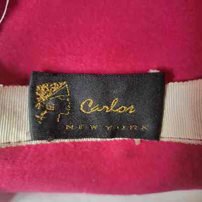The image shows a black label with gold text reading "Carlos New York" sewn onto pink fabric.