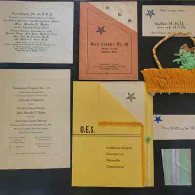 A black scrapbook page with multiple shapes and sizes of ephemera attached.