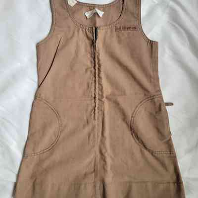 A brown jumper with pockets bears a "Girl Scouts USA" emblem visible on the chest area