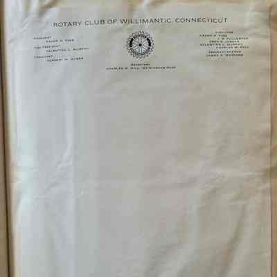 White letterhead with black lettering and a black circular emblem of a gear, on a beige background. The paper is wrinkled around the edges where wet glue was used to adhere it to the background.