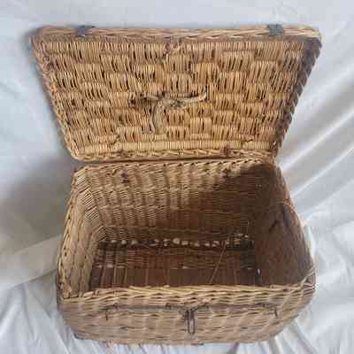 A large, open, woven wicker basket sits on a white fabric backdrop