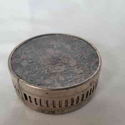 A vintage round tin features an intricate floral design on its bottom