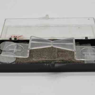 The image shows a plastic container holding three clear plastic weights and a layer of foam inside.