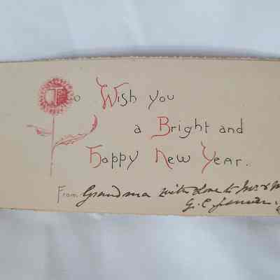 The image shows a handwritten New Year’s card with a floral design and signature.