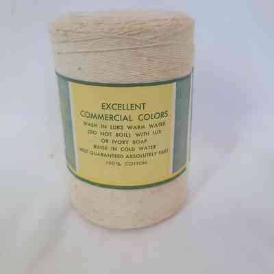 The image shows a roll of 100% cotton yarn with washing instructions printed on its label.