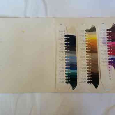 The image shows a color sample book with various thread shades attached to a white page.
