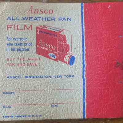The back of the cardboard booklet. The right third is red, bordered with thin blue and white stripes. The rest is white with red and blue lettering and a red illustration of a box of film.