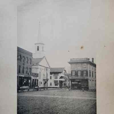 Photo caption reads: MAIN AND UNION STREETS. BAPTIST CHURCH. This Baptist church has been in operation since 1858 and continues as of 2024. At this junction Main St. split into Main St. and Union St., Union to the left in the photograph and Main in the foreground.