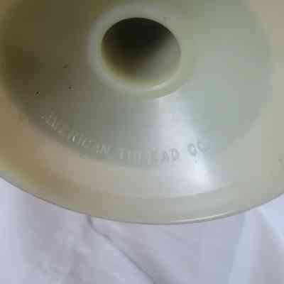 The image shows a close-up of a beige spool marked with "AMERICAN THREAD CO."