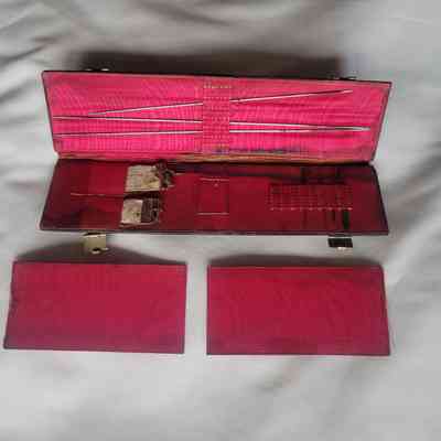 The image shows an open red needle case containing various sewing needles and some small labels inside.
